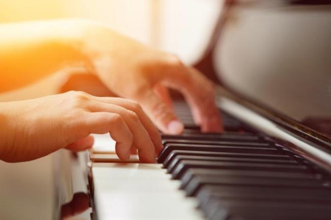 Adobe Express -   Side angle of pianist hands playing piano gently with enjoyment in the warm color tone with selective focus, concept piano player, playing music, pianist performance, piano performer, music education.